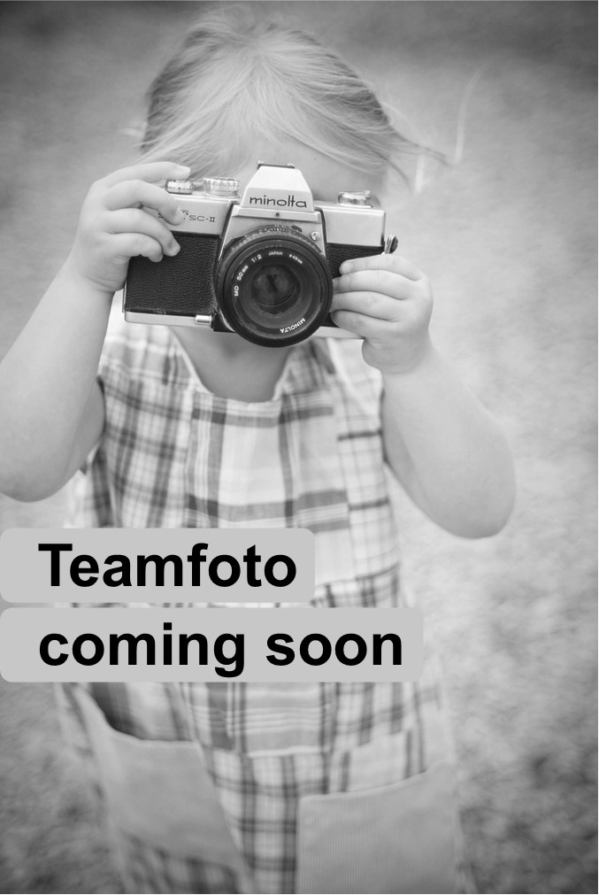 Auf dem Bild ist ein Kind, welches eine Kamera vor sein gesicht hält zu sehen. In der unteren Bildhälfte findet sich zudem die Aufschrift: "Teamfoto coming soon" (Englisch für "Teamfoto kommt bald"). 